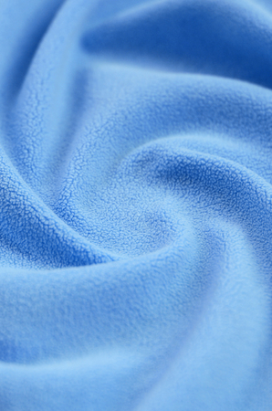 The blanket of furry blue fleece fabric. A background of light blue soft plush fleece material with a lot of relief foldsの写真素材