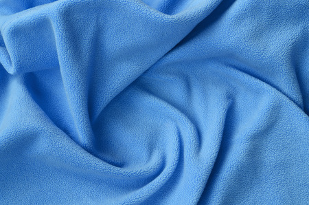 The blanket of furry blue fleece fabric. A background of light blue soft plush fleece material with a lot of relief foldsの写真素材