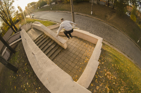 A young guy performs a jump through the space between the concrete parapets. The athlete practices parkour, training in street conditions. The concept of sports subcultures among youthの写真素材