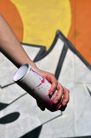 Photo of a girl's hand with aerosol paint cans in hands on a graffiti wall background. The concept of street art and use of aerosol paints. Graffiti art shop background imageの写真素材
