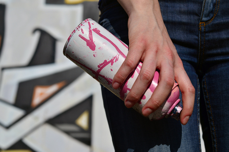 Photo of a girl's hand with aerosol paint cans in hands on a graffiti wall background. The concept...