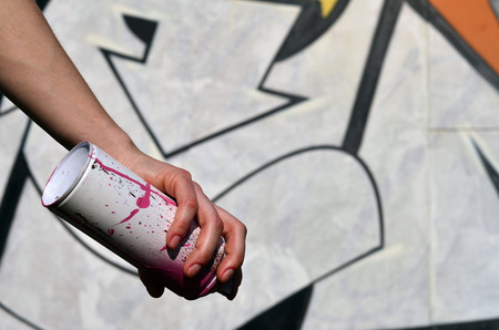 Photo of a girl's hand with aerosol paint cans in hands on a graffiti wall background. The concept of street art and use of aerosol paints. Graffiti art shop background imageの写真素材