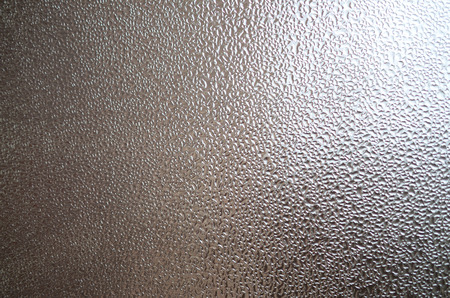A photo of the glass surface of the window, covered with a multitude of droplets of various sizes. Background texture of a dense layer of condensate on glassの写真素材