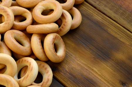 A lot of fresh yellow bagels lie on the surface of the old dark wood. A popular kind of flour products. One of the traditional Russian treats for teaの写真素材