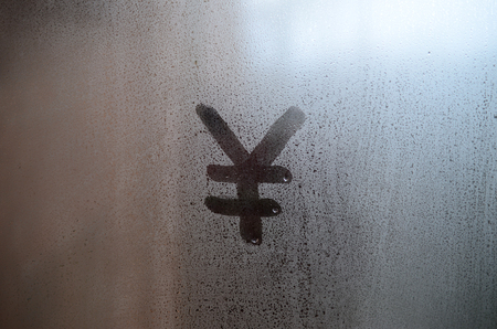 Chinese Yen Symbol is written with a finger on the surface of the misted glassの写真素材
