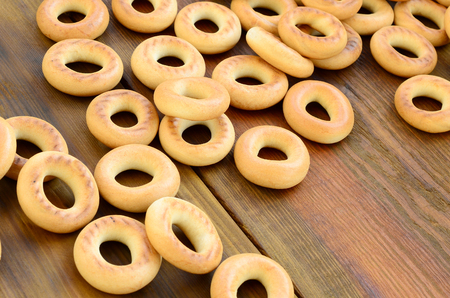 A lot of fresh yellow bagels lie on the surface of the old dark wood. A popular kind of flour products. One of the traditional Russian treats for teaの写真素材