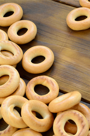 A lot of fresh yellow bagels lie on the surface of the old dark wood. A popular kind of flour products. One of the traditional Russian treats for teaの写真素材