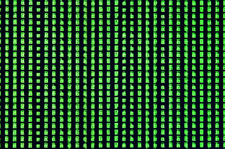Macro shot of a glitch on the monitor of an office computer. The concept of introducing a virus into a personal data keeper. Stream of random green symbols on a black backgroundの写真素材