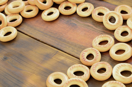 A lot of fresh yellow bagels lie on the surface of the old dark wood. A popular kind of flour products. One of the traditional Russian treats for teaの写真素材