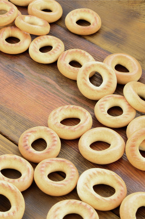 A lot of fresh yellow bagels lie on the surface of the old dark wood. A popular kind of flour products. One of the traditional Russian treats for teaの写真素材