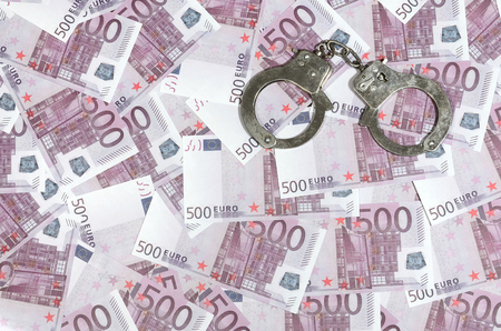 Handcuffs on five hundred euros background. Financial crime, dirty money and corruption concept - 500 money bills and dirty steel handcuffsの写真素材
