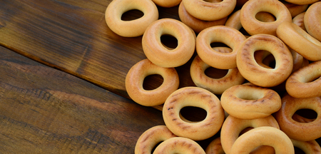 A lot of fresh yellow bagels lie on the surface of the old dark wood. A popular kind of flour products. One of the traditional Russian treats for teaの写真素材