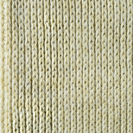 Fabric texture of a soft yellow knitted sweater. Macro image of the structure of bindings in yarnsの写真素材