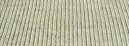 Fabric texture of a soft yellow knitted sweater. Macro image of the structure of bindings in yarns