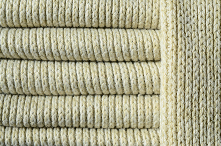 Composition of a soft yellow knitted sweater. Macro texture of bindings in yarns