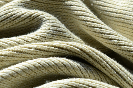 Fabric texture of a soft yellow knitted sweater. Macro image of the structure of bindings in yarnsの写真素材