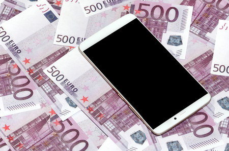 Purple 500 euro money bills and a smartphone with black screen. Copy space. The concept of online banking, money management and shopping with modern technologyの写真素材