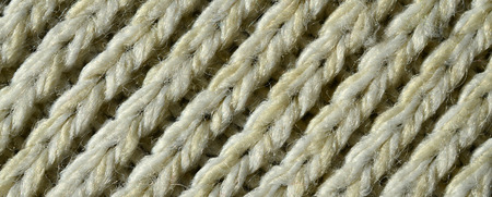 Fabric texture of a soft yellow knitted sweater. Macro image of the structure of bindings in yarnsの写真素材