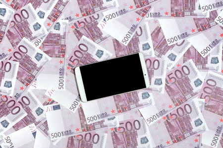 Purple 500 euro money bills and a smartphone with black screen. Copy space. The concept of online banking, money management and shopping with modern technologyの写真素材