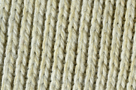 Fabric texture of a soft yellow knitted sweater. Macro image of the structure of bindings in yarnsの写真素材