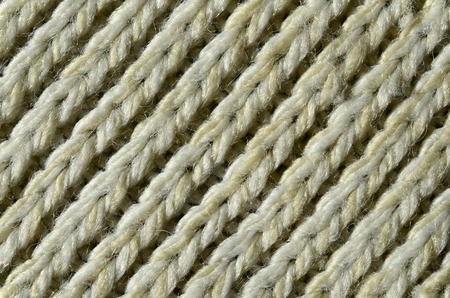 Fabric texture of a soft yellow knitted sweater. Macro image of the structure of bindings in yarnsの写真素材