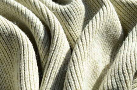Fabric texture of a soft yellow knitted sweater. Macro image of the structure of bindings in yarnsの写真素材