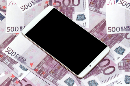 Purple 500 euro money bills and a smartphone with black screen. Copy space. The concept of online banking, money management and shopping with modern technologyの写真素材