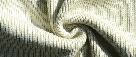 Fabric texture of a soft yellow knitted sweater. Macro image of the structure of bindings in yarnsの写真素材