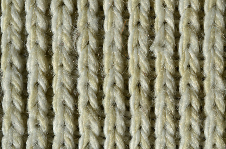 Fabric texture of a soft yellow knitted sweater. Macro image of the structure of bindings in yarnsの写真素材