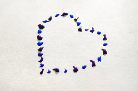 Image of a heart made from wet drops of watercolor paint on a paper sheetの写真素材