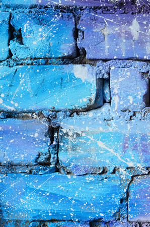 The texture of the old brick wall, painted in blue and purple colors with carelessly spaced white drops and splashes that visualize the stars in outer spaceの写真素材