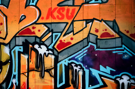 A fragment of detailed graffiti of a drawing made with aerosol paints on a wall of concrete tiles....