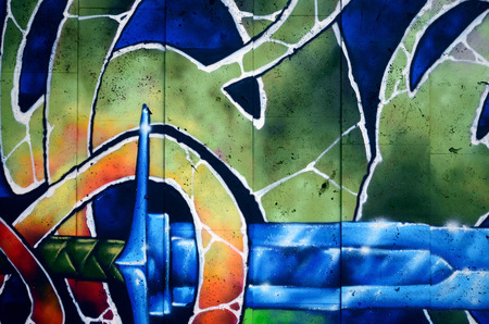 A fragment of detailed graffiti of a drawing made with aerosol paints on a wall of concrete tiles. Background image of street art with a fairy-tale crystal swordの写真素材