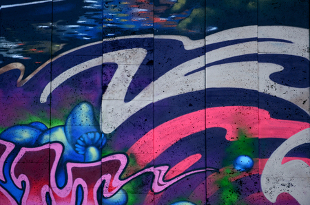 A fragment of detailed graffiti of a drawing made with aerosol paints on a wall of concrete tiles. Background image of street art with fairy blue mushroomsの写真素材