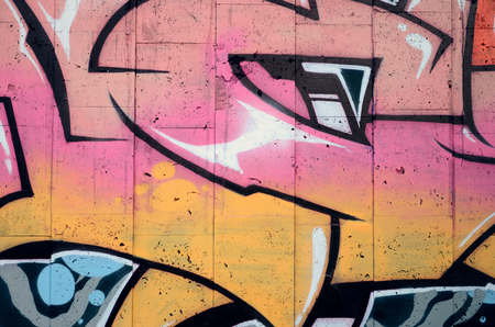 A fragment of detailed graffiti of a drawing made with aerosol paints on a wall of concrete tiles. Background image of street art in beige and pink color tonesの写真素材