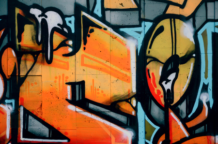 A fragment of detailed graffiti of a drawing made with aerosol paints on a wall of concrete tiles. Background image of street art in warm red color tonesの写真素材