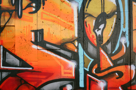 A fragment of detailed graffiti of a drawing made with aerosol paints on a wall of concrete tiles. Background image of street art in warm red color tonesの写真素材