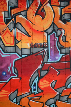 A fragment of detailed graffiti of a drawing made with aerosol paints on a wall of concrete tiles. Background image of street art in warm red color tonesの写真素材