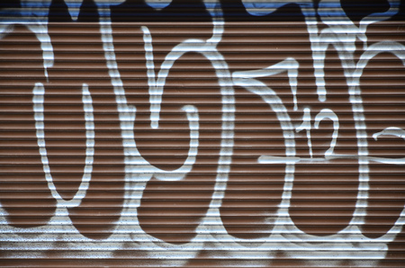 Fragment of an old colored graffiti drawing on the shutter door. Background image as an illustration of street art, vandalism and wall painting with aerosol paintの写真素材