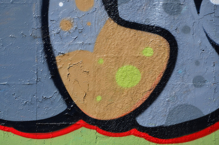 Fragment of an old colored graffiti drawing on the wall. Background image as an illustration of street art, vandalism and wall painting with aerosol paintの写真素材