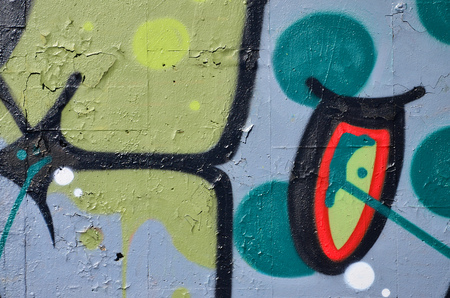 Fragment of an old colored graffiti drawing on the wall. Background image as an illustration of street art, vandalism and wall painting with aerosol paintの写真素材
