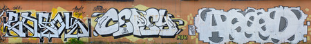 A photo of several graffiti artworks on the metal wall. Graffiti drawings are made with white paint with black outlines and have an orange background. Texture of wall with graffiti decorationの写真素材