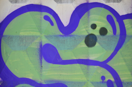 Fragment of an old colored graffiti drawing on the wall. Background image as an illustration of street art, vandalism and wall painting with aerosol paintの写真素材