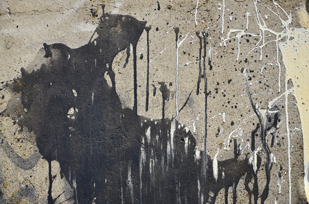 A photograph of a close-up of black paint spots on a concrete wall. Pouring paint on the wall in random order. The concept of graffiti and street art cultureの写真素材