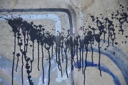 A photograph of a close-up of black paint spots on a concrete wall. Pouring paint on the wall in random order. The concept of graffiti and street art cultureの写真素材