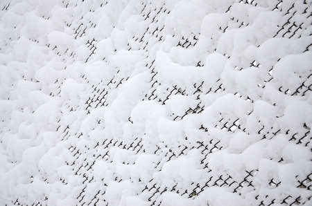 Close-up metal mesh covered with a thick layer of snow in the cellsの写真素材
