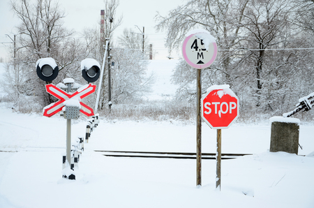 Stop. Red road sign is located on the motorway crossing the railway line in winter seasonの写真素材