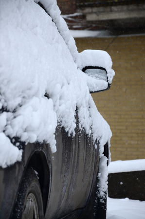 Fragment of the car under a layer of snow after a heavy snowfall. The body of the car is covered with white snowの写真素材