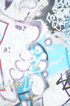 Close-up fragment of a graffiti drawing applied to the wall by aerosol paint. The wall is spoiled by a multitude of colorful signatures and tags from street artists and hooligansの写真素材