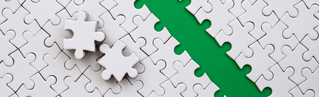 The green path is laid on the platform of a white folded jigsaw puzzle. The missing elements of the puzzle are stacked nearby. Texture image with space for textの写真素材